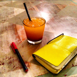 Appunti, penna rossa, e succo di arancia e bacche di goji